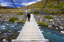 Hiker, Eulia Vicens, crossing a wooden bridge over Ascensio river on the W Trek, Torres del Paine National Park, Patagonia, Chile