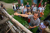 Joerg Mueller releasing a caught Grass snake (Natrix natrix) back into her hiding place, watched by adults and children, Oekowerk in the Grunewald, Berlin, Germany, August 2006