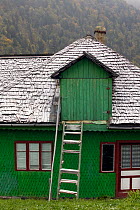 Peasant home with chestnut paling tiles covered in snow in alpine village. Romania, October 2010
