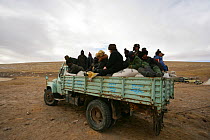 People riding on a truck stacked with sacks of poison. These are distributed to farmers as part of an annual compulsory cull to control the Tibetan Pika (Ochotona thibetana) population, Qinghai Provin...