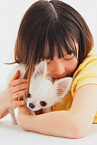 Portrait of young girl holding white Chihuahua puppy