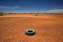Discarded truck tyre in the dry red desert of the Australian centre by the highway between Mt. Isa and Boulia. Queensland, Australia, February 2008
