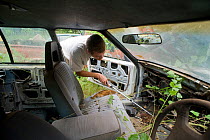 Researcher Guido Westhoff looking through a car dumpsite where snakes could be taking shelter under metal sheets or inside the car or engines. Queensland, Australia, February 2008