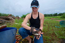 Snake breeder Lauren Collings with a Spotted python (Antaresia maculosa) in a trash dump site.  Queensland, Australia, February 2008