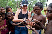 Lauren Collings, the local snake breeder from Weipa shows her pet spotted python (Antaresia maculosa) to the Aboriginal children of Napranum Aboriginal community. Queensland, Australia, February 2008