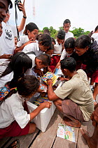 A ranger from the eco resort distributing a selection of books to the students of Yellu Village. Misool, Raja Ampat, West Papua, Indonesia, January 2010.