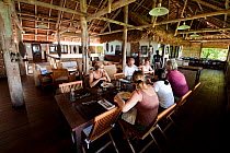 Group of people eating a meal in Sorido Bay Resort dining room area. Raja Ampat, West Papua, Indonesia, February 2010.