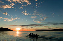 West Papuan fishermen in their outrigger boat at sunset. Raja Ampat, West Papua, Indonesia, February 2010.