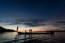 West Papuan fishermen in their dugout canoe at sunset. Raja Ampat, West Papua, Indonesia, February 2010.
