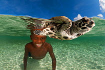 Papuan boy swimming in the shallows with his pet baby hawksbill turtle (Eretmochelys imbricata). Tunnung Island, New Hanover, Papua New Guinea, June 2010