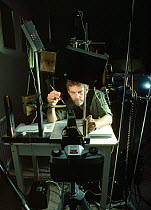 Photographer Stephen Dalton setting up photographic equipment to capture images of jumping spiders. The macro studio set up is shown, with camera and flashes. UK.