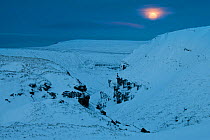Full moon over snow-covered Alport Castles, Peak District National Park, Derbyshire, UK, December 2009.