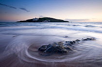 Burgh Island in the late evening light with seaweed washed onto the shore in the foreground. Bigbury-on-Sea, South Devon, UK, September 2010