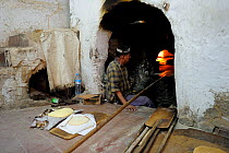 A man baking bread in a large oven. Medina quarter of Fes, Morocco, December 2010.