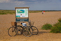 Two bicycles propped up against Blakeney NNR information sign, Cley Beach, North Norfolk, UK, September