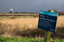 Sign informing of protection of sea defences, Burnham Norton marshes, Norfolk, UK