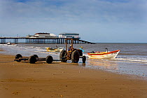 Tractor and trailer at shoreline waiting to collect crabbing boat, Cromer, UK