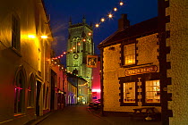 Lights decorating narrow street near church and pub at Christmas, Cromer, Norfolk, UK