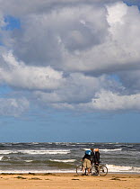 Man and woman on Holkham Beach with bicycles, North Norfolk Coast, UK