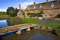 Traditional stone houses and bridge beside River Eye, Lower Slaughter Village, Cotswolds, Gloucestershire, UK