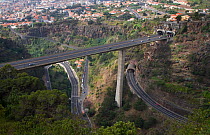 Aerial view of dual carriageway road carried by bridge high over a valley above other roads, near Funcal, Madeira, November