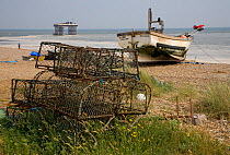 Lobster / crab pots and fishing boat on the beach at Sizewell, Suffolk, UK. June