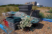 Beach landscape with fishing baskets in foreground and Sizewell nuclear energy reactor in background, Sizewell, Suffolk, UK