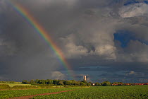 Rainbow ending at church, Southrepps, Norfolk, UK. March