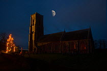 St James Church at night with Christmas tree and moon, South Repps, Norfolk, UK, December
