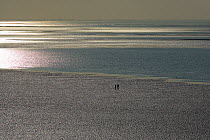 Two people walking along the beach on The Wash at low tide, Hunstanton, Norfolk, UK, March 2006