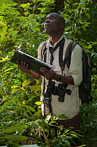 Senior field assistant Geresomu Muhumuza recording indiviudal behavioural data of chimpanzees (Pan troglodytes schweinfurthii). Budongo Forest Reserve, Masindi, Uganda, Africa. December 2006