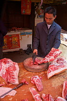 Chinese butcher preparing pork and cow meat in the market of Zhouzhi town, Qinling Mountains, Shaanxi, China, March 2006