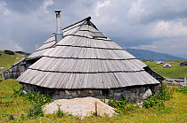 Traditional wooden herdsman's hut with pine shingle roof and modern solar panel installed on 1600m high pastureland at Velika Planina plateau, Kamnik-Savinja Alps, Slovenia, July 2010.