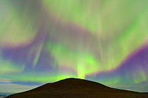 Northern lights (Aurora Borealis) in sky above a hill by Jokulsarlon glacier lagoon. Southern Iceland, Europe, March 2011.