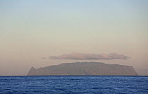 Inaccessible Island on the horizon topped with clouds. UNESCO World Heritage site and part of the Tristan da Cunha Group of South Atlantic Islands, March 2007.