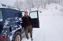 Pete Cairns, photographer, beside four-wheel drive vehicle in Silver birch (Betula pendula) woodland in winter, Glenfeshie, Cairngorms NP, Highlands, Scotland, UK, December 2010