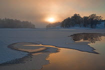 Loch Insh in winter, partially frozen and covered in snow, low sun, Cairngorms NP, Highlands, Scotland, UK, December