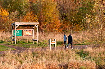 Walkers passing information shelter in Sence Valley Forest Park, the site of a former colliery, New plantation, autumn, Leicestershire, UK. November 2010.