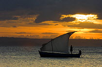 Fishermen on their boat in front of sunlit clouds. Ramena beach, Diego Suarez (Antsiranana) in north Madagascar, June 2007.