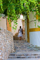 A woman walking up steps in a Mediterranean town. Ibiza Island, Balearic Islands, Spain.