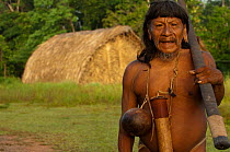Portrait of a Huaorani man with his blowgun in front of traditional forest dwellings. Bameno Community, Yasuni National Park Ecuador, May, 2007. Model release B#1.
