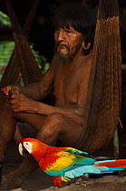 Huaorani man with his pet Scarlet Macaw (Ara macao). Gabaro Community, Yasuni National Park, Ecuador, June 2007. Model release #GA03.