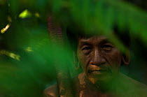 A Huaorani man seen through leaves in the forest undergrowth. Gabaro Community, Yasuni National Park, Ecuador, June 2007. Model release #GA21.