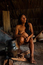 Huaorani Indian woman drying her home-made ceramic pot on the fire after washing it out. Gabaro Community, Yasuni National Park, Ecuador, June 2007. Model release #GA12.