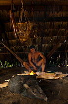 Huaorani Indian cooking a peccary that he hunted. Gabaro Community, Yasuni National Park, Ecuador, June 2007. Model release #GA07.