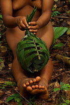Huaorani Indian girl making a basket from palm leaves. These are one time use baskets to carry things home and then are discarded. Gabaro Community, Yasuni National Park, Ecuador, June 2007.