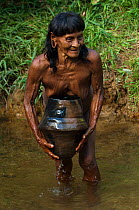 Huaorani Indian woman using a clay pot for carrying water from the river. The Huaorani clay pots have a unique shape compared with any of the other indian tribes in Ecuador. Gabaro Community, Yasuni N...