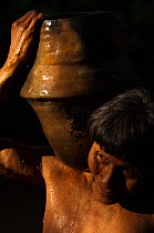 Huaorani Indian woman using a clay pot for carrying water from the river. The Huaorani clay pots have a unique shape compared with any of the other indian tribes in Ecuador. Gabaro Community, Yasuni N...