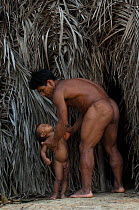 Huaorani Indian and his child outside their forest dwelling. Bameno Community, Yasuni National Park, Ecuador, May 2007. Model release B#6.