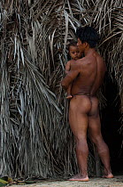 Huaorani Indian and his child outside their forest dwelling. Bameno Community, Yasuni National Park, Ecuador, May 2007. Model release B#6.